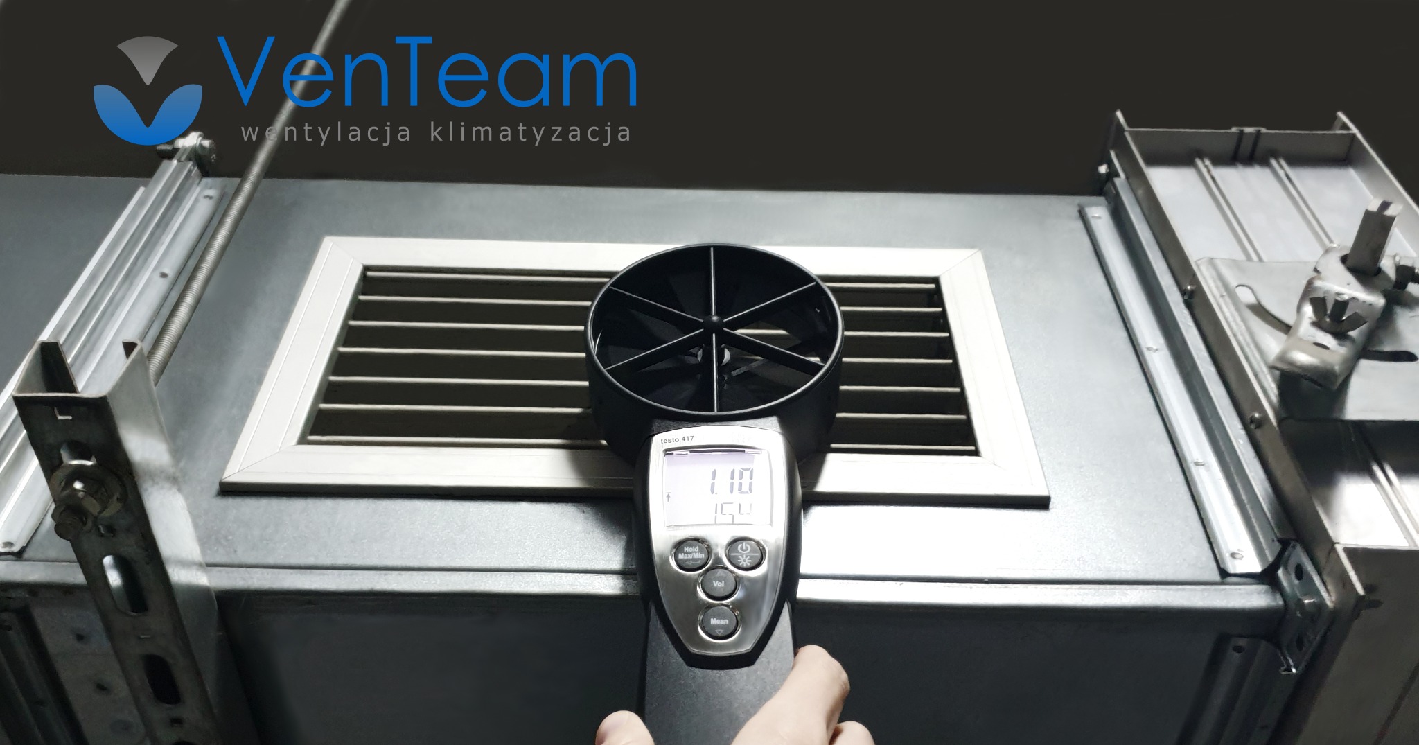 Pomiar przepływu powietrza anemometrem Testo 417 przy kratce wentylacyjnej w instalacji wentylacyjnej, widoczne logo firmy VenTeam.