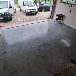 Floorwit Vitalii Mezhduhornyi - Gładka, ciemnoszara posadzka żywiczna lub mikrocementowa z widocznymi dylatacjami i odwodnieniem liniowym w nowym garażu w Bielsku-Białej, z otwartą bramą i zaparkowanymi autami.