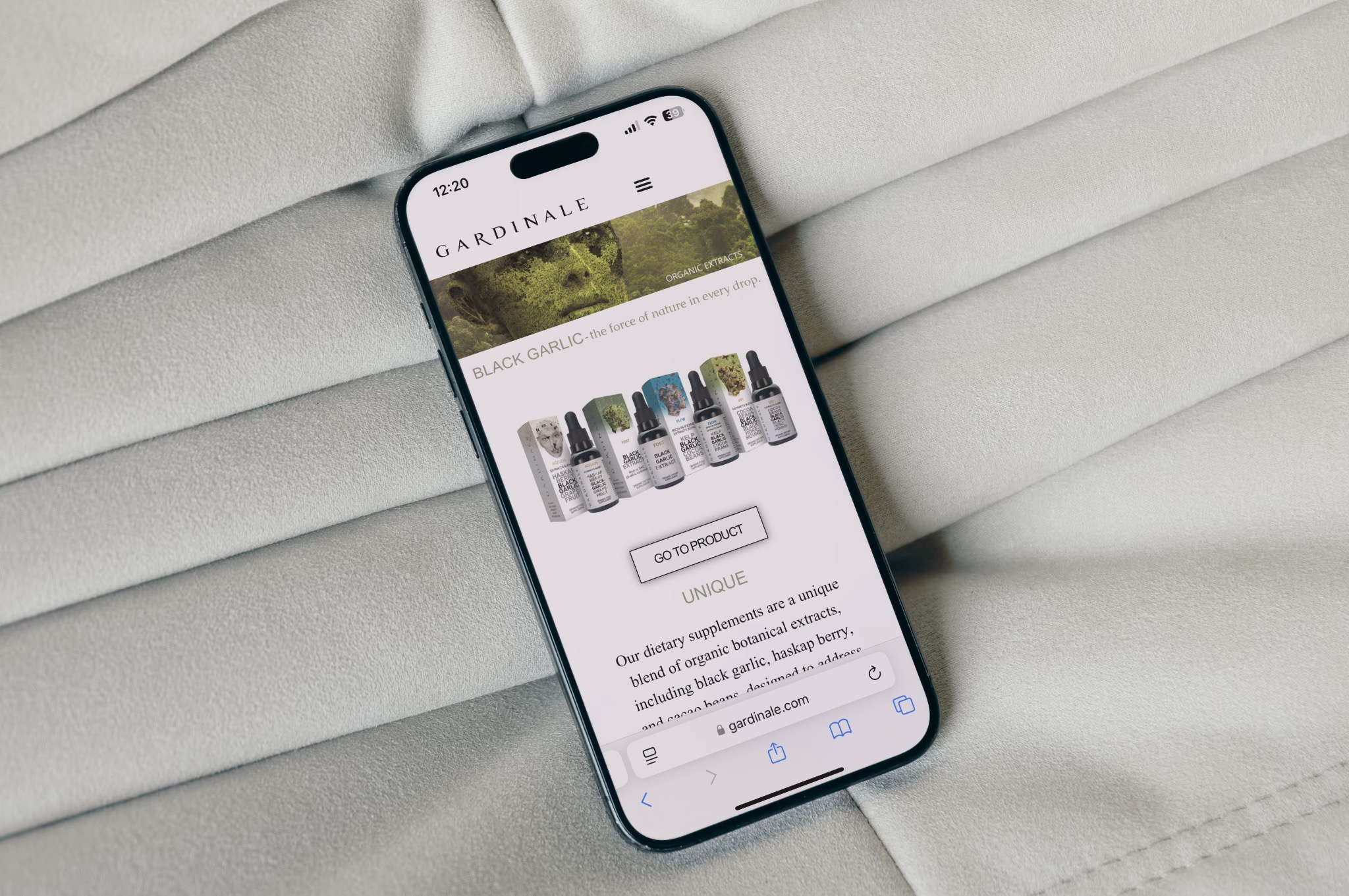 Smartfon wyświetlający stronę internetową marki Gardinale z produktami z czosnku, leżący na jasnoszarym, teksturowanym tle.