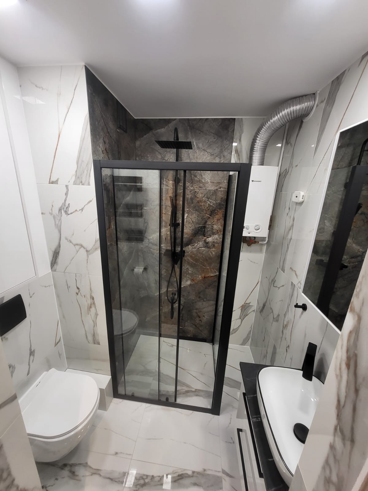 Nowoczesna łazienka z kabiną prysznicową typu walk-in, marmurowymi płytkami i czarną armaturą, oświetlona ledowym światłem. Grzejnik w tle.