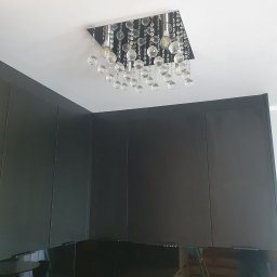 Apo-Inwestment Artur Popis - Nowoczesna lampa sufitowa z kryształkami w kwadratowej oprawie, zamontowana w ciemnej kuchni z błyszczącymi szafkami.