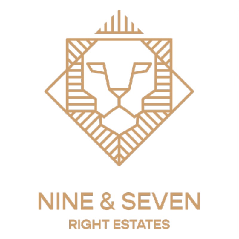 Minimalistyczne logo firmy 'Nine & Seven Right Estates' przedstawiające geometryczną głowę lwa w kolorze beżowym na białym tle.
