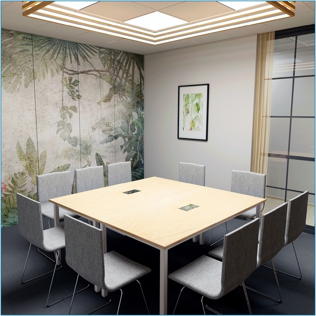 Sala konferencyjna z tapetą w motywy roślinne, jasnym stołem z wbudowanymi gniazdami i szarymi krzesłami na metalowych nogach, oświetlona panelami LED w suficie.