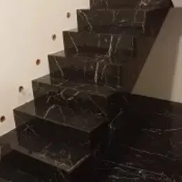 Schody wyłożone czarnym marmurem z białymi żyłkami w Leoncinie, widoczne otwory na oświetlenie w ścianie.