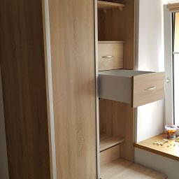 Darek Piotrowski Renowacja mebli , meble na wymiar. - Jasna szafa wnękowa z przesuwnymi drzwiami i wysuwanymi elementami w Jeleniej Górze, widok na otwartą szufladę i wysuwany blat roboczy.