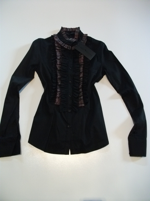 Czarna bluzka damska z falbanami i stójką, widoczna metka producenta, leżąca na białym tle.