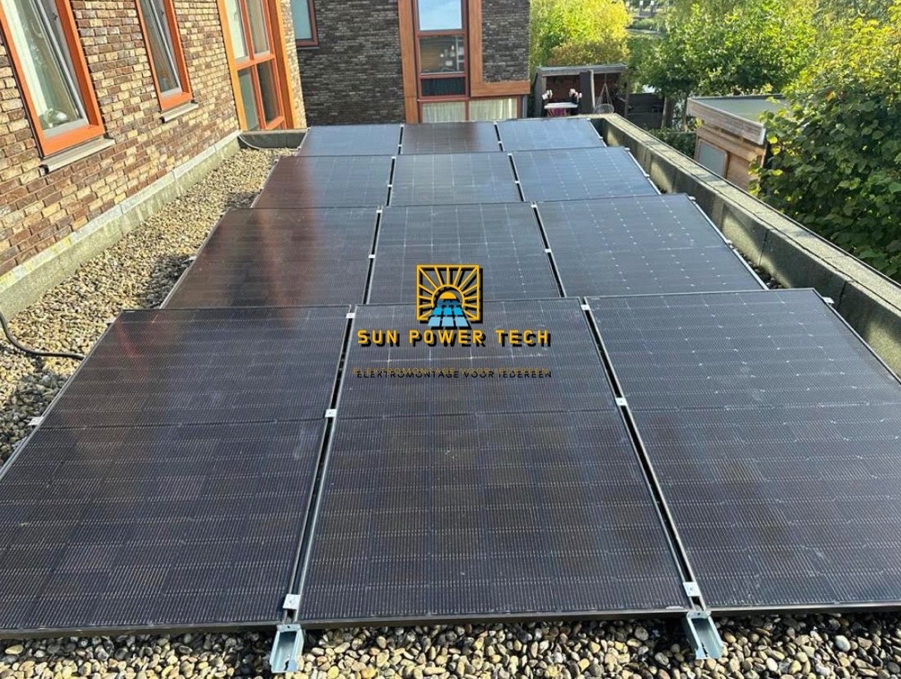 Instalacja fotowoltaiczna na płaskim dachu pokrytym żwirem, widoczne panele z logo 'SUN POWER TECH'.