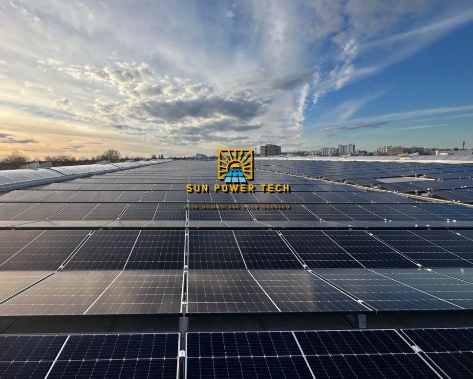 Rozległa instalacja paneli słonecznych na dachu budynku, widok z góry, logo firmy Sun Power Tech wkomponowane w kadr, błękitne niebo z chmurami w tle.