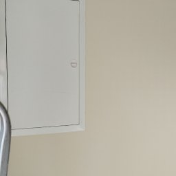 Ambika PL - Biała klapa rewizyjna na beżowej ścianie, widoczny fragment drabiny malarskiej.