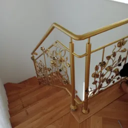 Złota, dekoracyjna balustrada z motywem roślinnym na drewnianych schodach w Toruniu, widok z góry.
