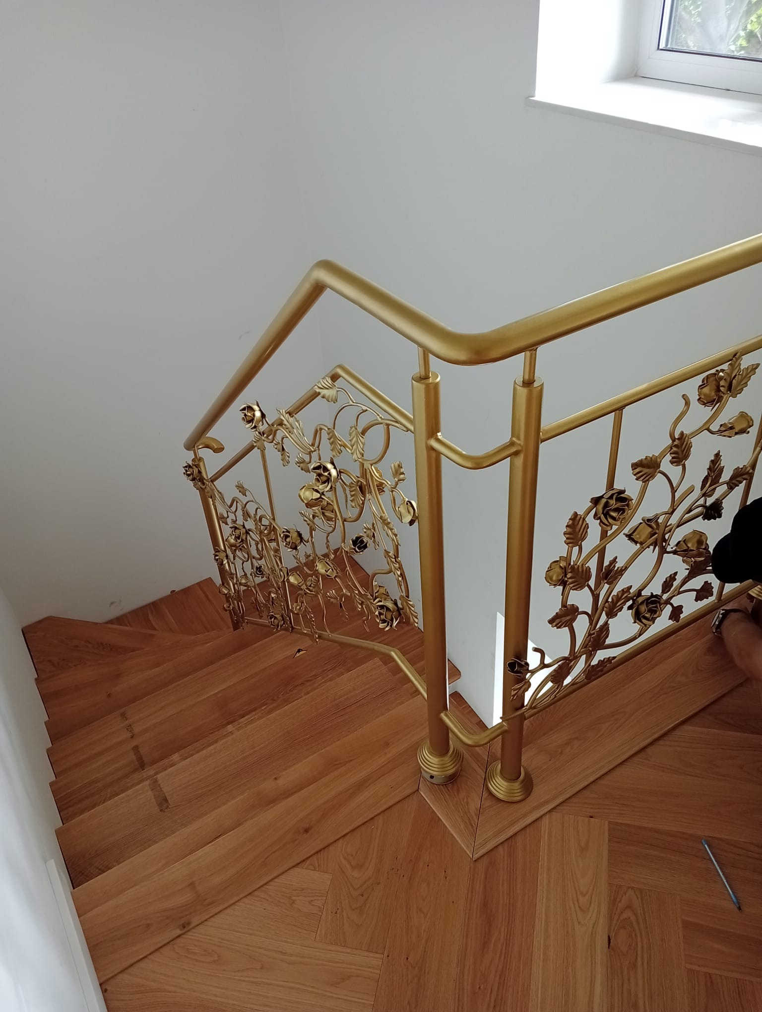 Złota, dekoracyjna balustrada z motywem roślinnym na drewnianych schodach w Toruniu, widok z góry.