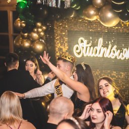 Bartosz Glasek Photo - Uczestnicy studniówki w trakcie zabawy, widoczny napis 'Studniówka' z dekoracjami balonowymi w tle. Młodzież w strojach wieczorowych.