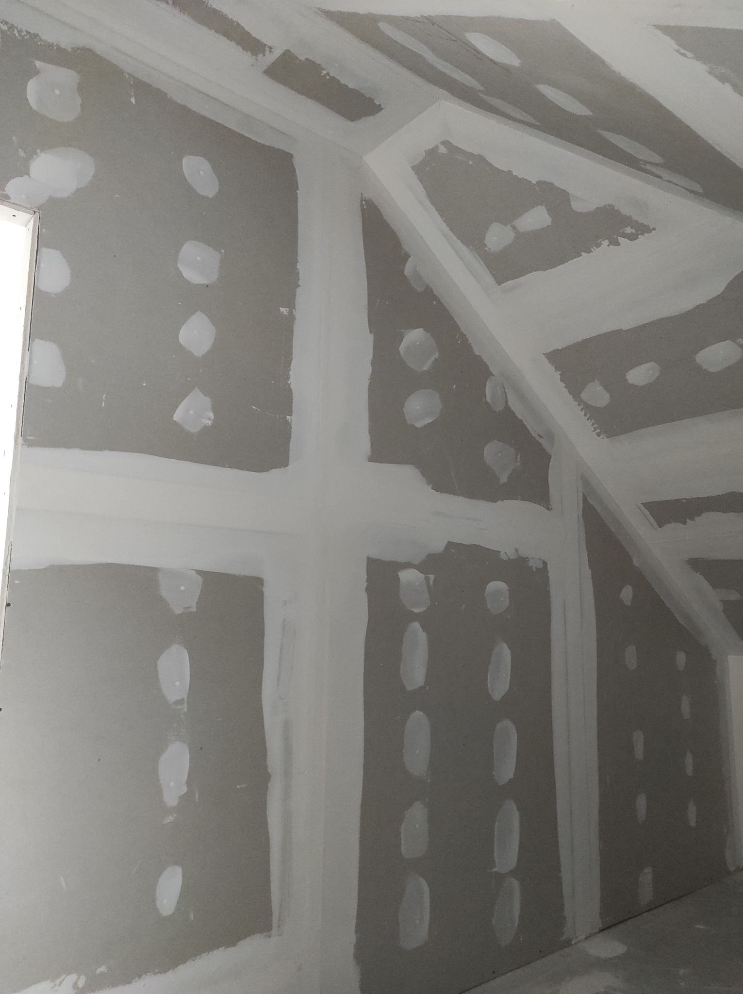 Płyty gipsowo-kartonowe na poddaszu, szpachlowane łączenia i wkręty, surowy stan przed malowaniem.