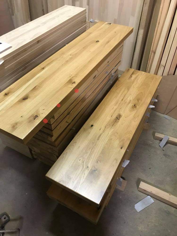 Stos wysezonowanych, surowych blatów z jasnego drewna dębowego, widoczne sęki i naturalny rysunek słojów, przygotowane do dalszej obróbki.