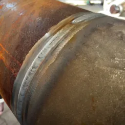 Spoina na rurze ze śladami korozji, widoczna struktura spawu.