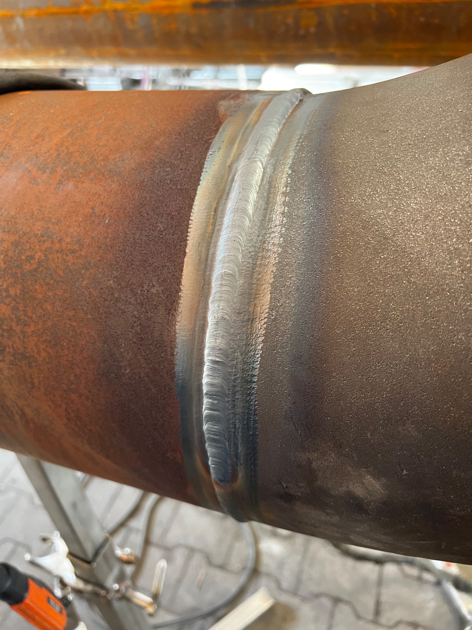 Spoina na rurze, widoczne ślady rdzy na powierzchni metalu, świeży spaw o wyraźnej strukturze.