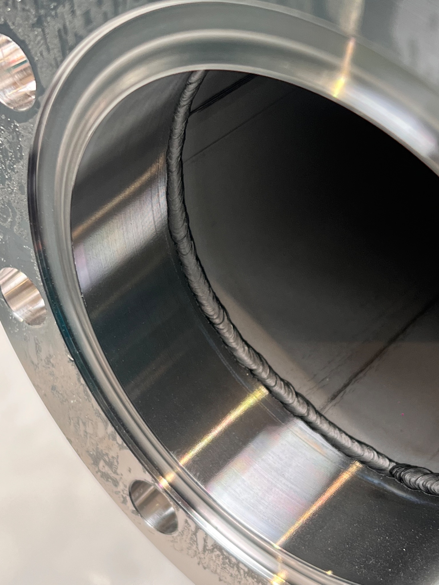 Wewnętrzny spaw na metalowej flanszy z widocznymi śladami obróbki i zgrubieniami spoiny.