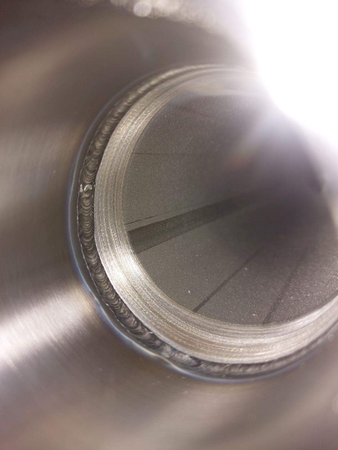 Wnętrze rury ze stali nierdzewnej, widoczny spaw okrężny z charakterystyczną strukturą, wykonany metodą TIG, z delikatnymi przebarwieniami termicznymi.