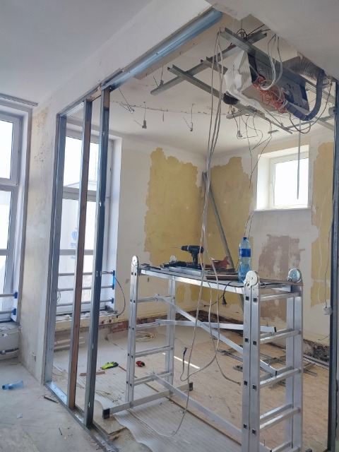 Montaż metalowej konstrukcji ścianki działowej w trakcie remontu mieszkania w Gdańsku, widoczny stelaż, drabina, narzędzia i nieotynkowane ściany.