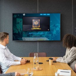 Reflekz Studio - Zespół w biurze ogląda prezentację studia graficznego na dużym ekranie, z widokiem miasta za oknem.