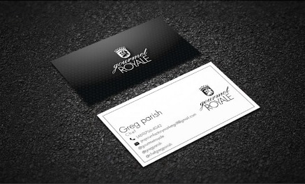 Dwie wizytówki firmy Gourmet Royale, jedna czarna z białym napisem, druga biała z czarnym napisem, leżące na ciemnym, teksturowanym tle.