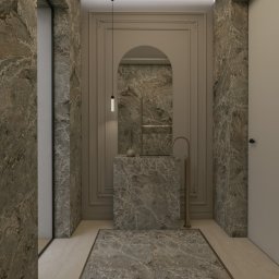 Solo Design Studio Izabela Czerwik - Luksusowa łazienka z marmurowymi ścianami, podłogą i umywalką. Złota armatura i ozdobne listwy dodają elegancji wnętrzu. Nad umywalką wisi lustro w kształcie łuku.