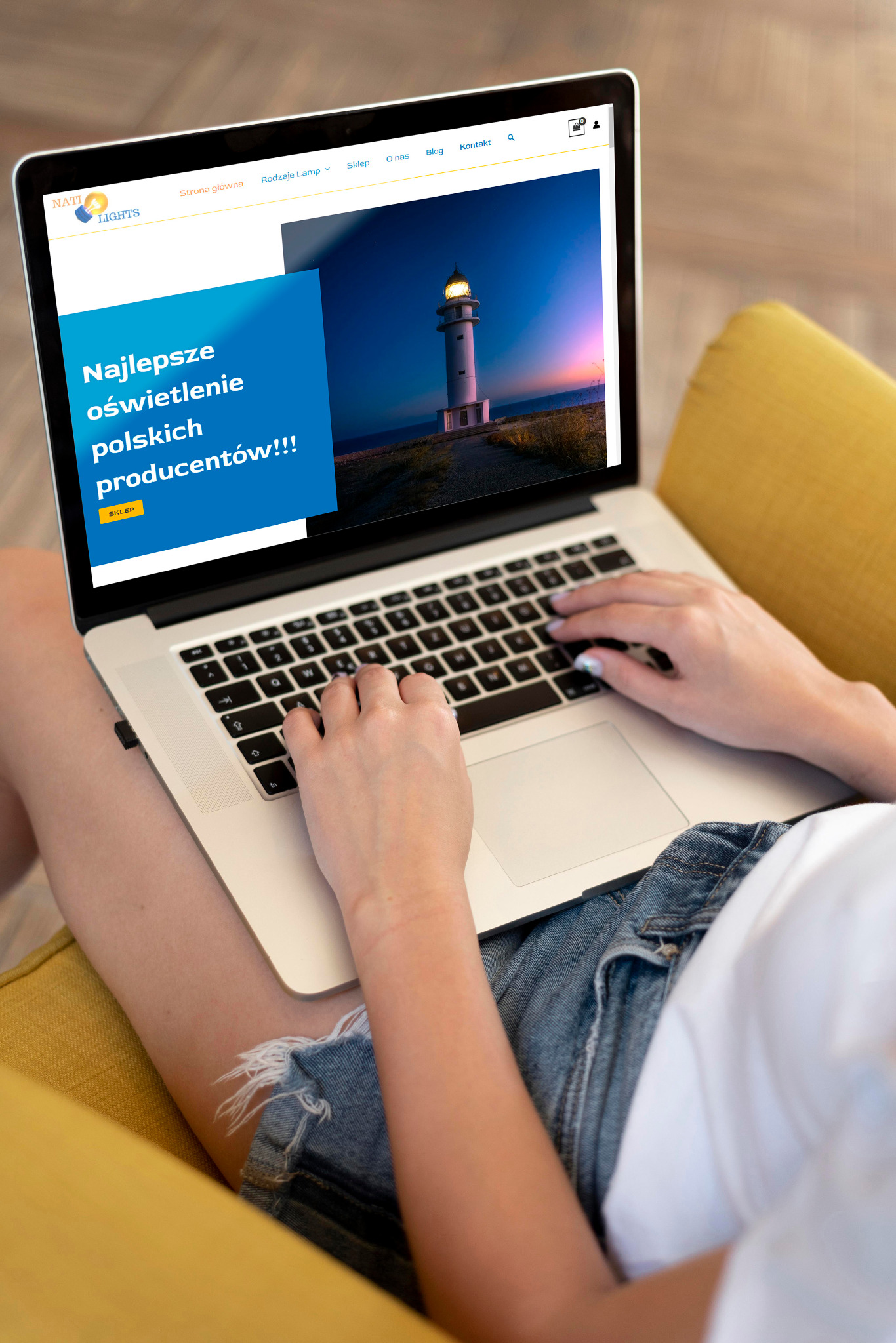 Osoba siedząca na żółtej sofie, używająca laptopa z otwartą stroną internetową prezentującą białą latarnię morską na tle zachodzącego słońca i hasłem 'Najlepsze oświetlenie polskich producentów!!!'
