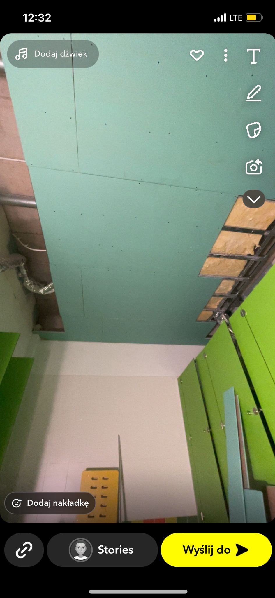 Montaż zielonej płyty karton-gips na suficie, widoczne profile konstrukcyjne i fragment instalacji. Ujęcie z dołu, z widocznymi elementami pomieszczenia.