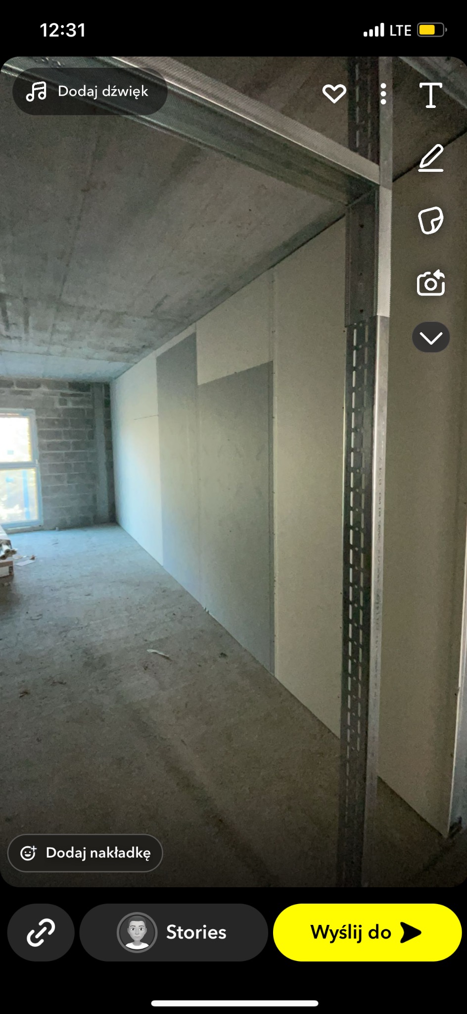 Montaż płyt karton-gips na metalowym stelażu w surowym wnętrzu. Widoczny fragment okna i betonowy strop. Ujęcie z niskiej perspektywy, podkreślające wysokość pomieszczenia.