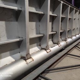 MikusMetal - Wnętrze stalowej konstrukcji hali w trakcie budowy, widoczne spawy i elementy nośne, zarysowane okręgi na ścianach.