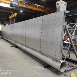 MikusMetal - Długa, spawana konstrukcja stalowa w hali produkcyjnej, podnoszona suwnicą z napisem 3200kg, widoczne spawane elementy i rura wzdłuż dolnej krawędzi.