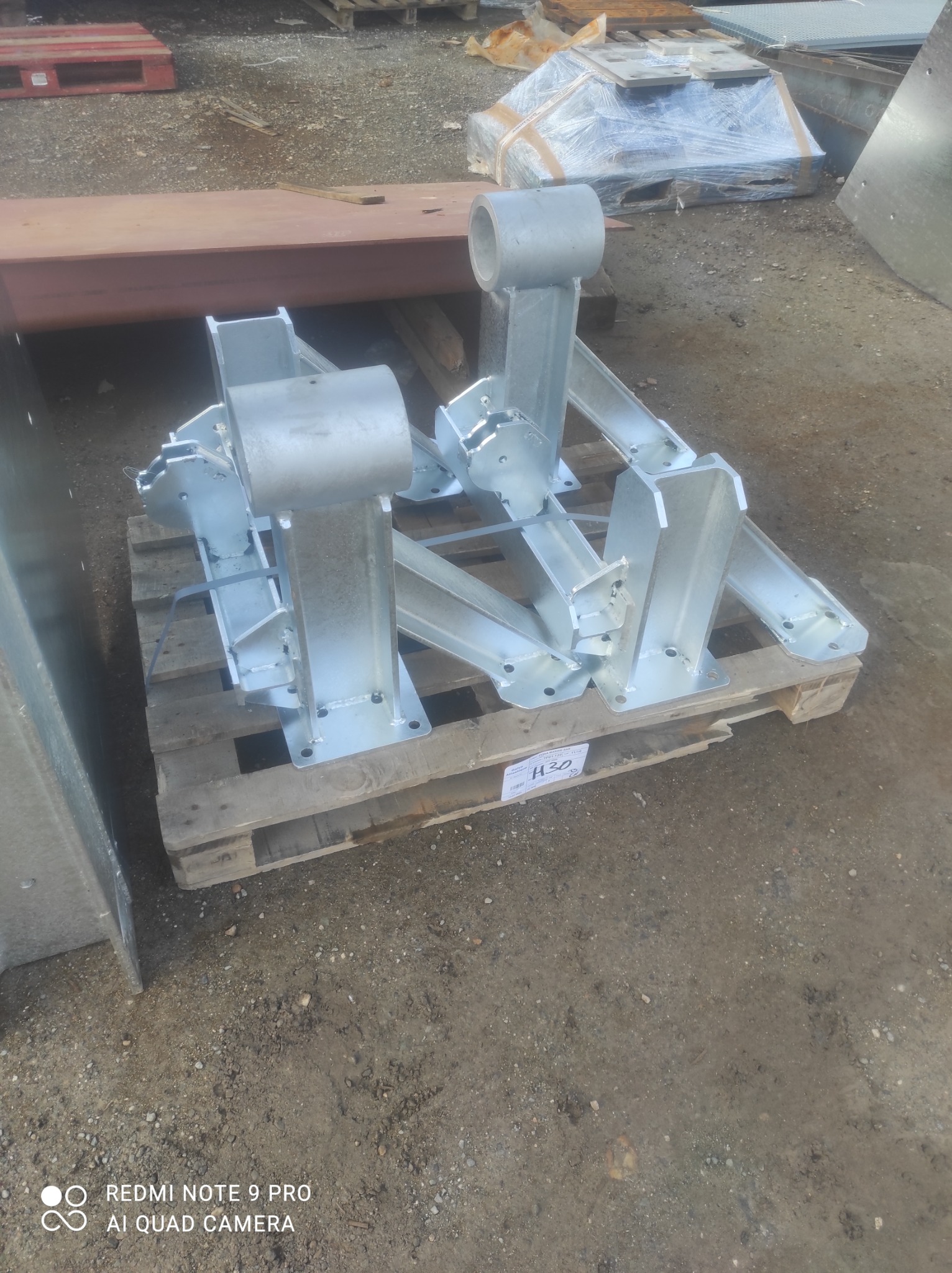 Ocynkowane, spawane elementy stalowe, prawdopodobnie wsporniki, ułożone na palecie w magazynie lub na placu budowy.