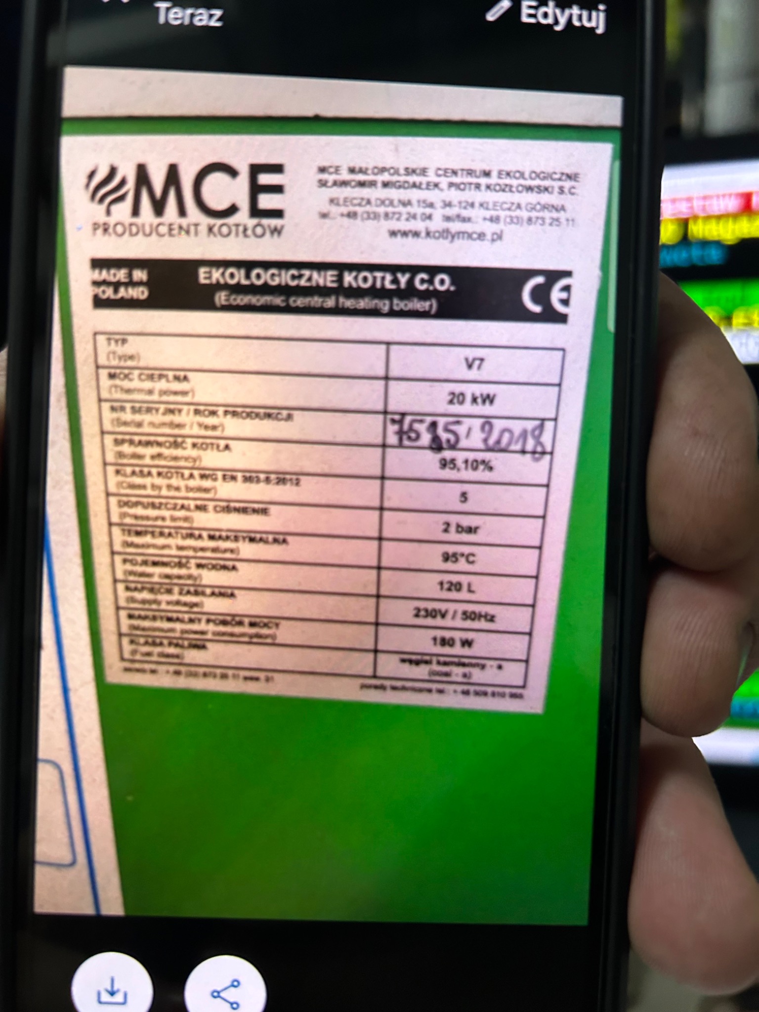 Zdjęcie ekranu smartfona prezentującego etykietę kotła C.O. firmy MCE z informacjami technicznymi, w tym moc cieplna 20 kW, rok produkcji 2018, sprawność 95,10% i klasa kotła 5.