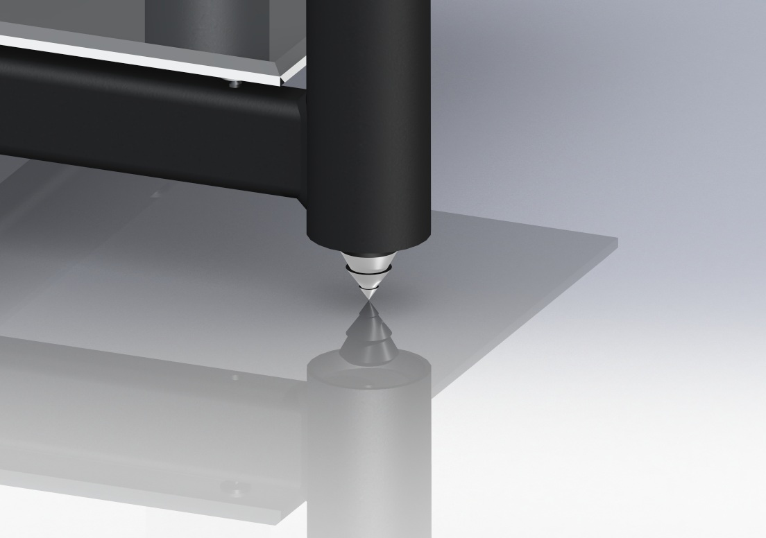 Detal nóżki metalowej konstrukcji, z widocznym ostrym zakończeniem i odbiciem na powierzchni, na tle szaro-białym.