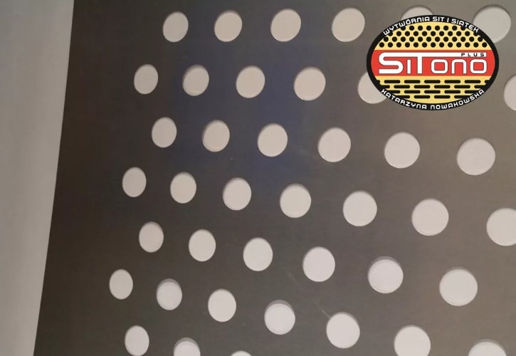 Metalowa płyta z regularnym wzorem okrągłych otworów, w prawym górnym rogu logo firmy 'Sitono Plus' z napisem 'Wytwórnia sit i siatek'
