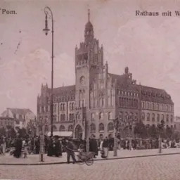 Stara pocztówka przedstawiająca budynek ratusza z wieżą zegarową, plac targowy z ludźmi i straganami w Słupsku (Stolp i. Pom.), Polska, w sepii.