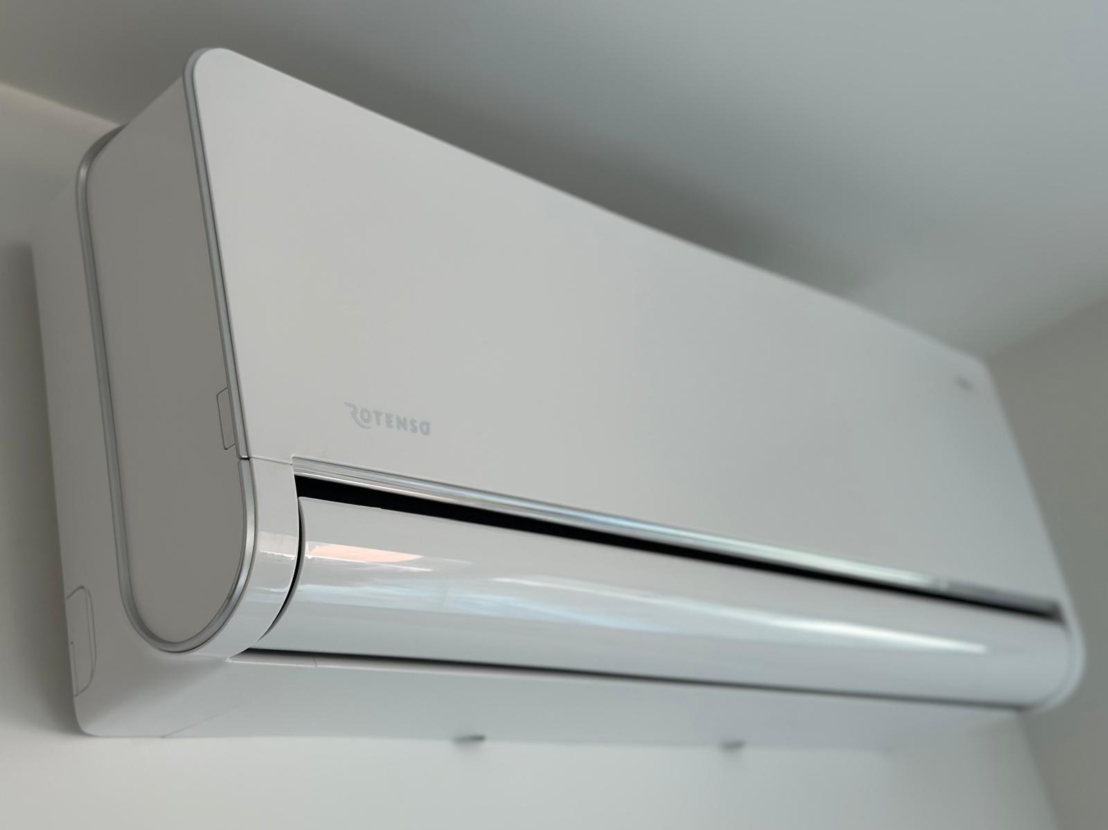 Biała jednostka wewnętrzna klimatyzacji marki Rotenso zamontowana na ścianie, widok z dołu pod kątem.