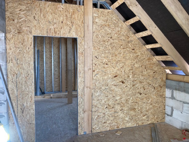 Montaż ścianek działowych z płyty OSB w Bielsku Podlaskim; widoczna konstrukcja szkieletowa z metalowych profili i fragment ocieplenia poddasza.