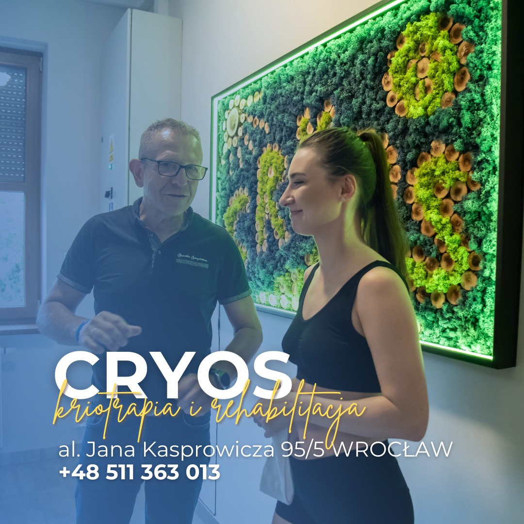 Mężczyzna w okularach rozmawia z uśmiechniętą kobietą w czarnym stroju sportowym na tle ściany z mchu w gabinecie rehabilitacyjnym.