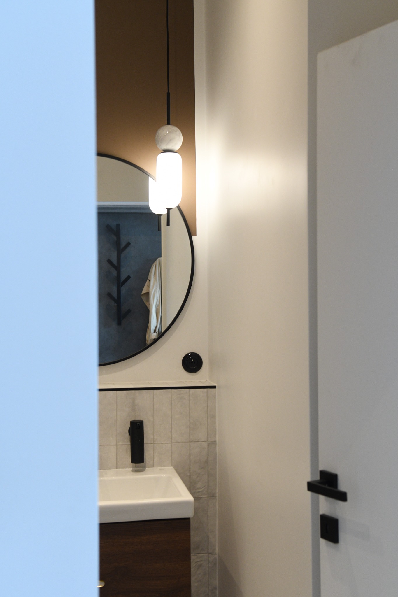 Nowoczesna łazienka w Kielcach z okrągłym lustrem, minimalistyczną umywalką z szafką z ciemnego drewna i wiszącą lampą z marmurową kulą.