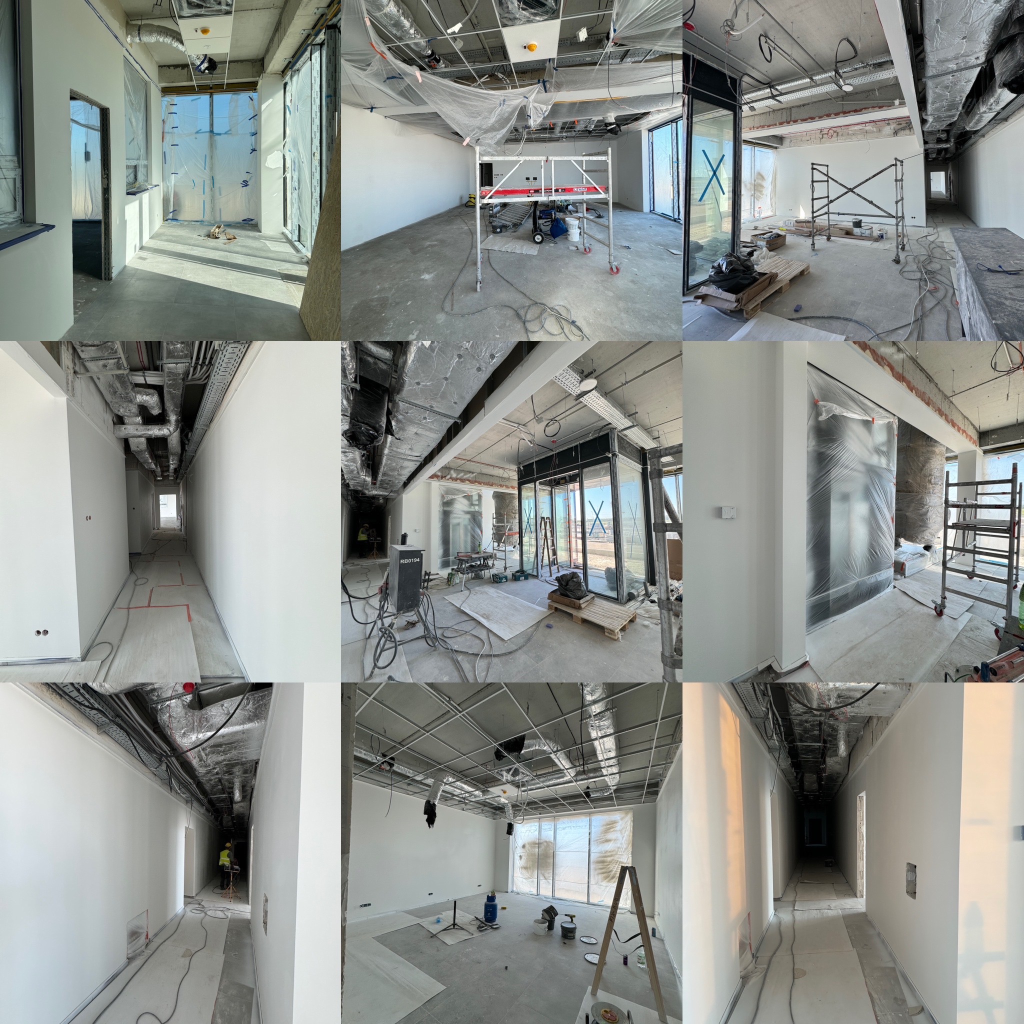 Wnętrze biurowe w trakcie prac wykończeniowych: ściany po szpachlowaniu i malowaniu na biało, widoczne instalacje pod sufitem, okna zabezpieczone folią, rusztowania i narzędzia malarskie.