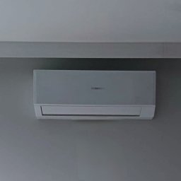 NOVEL ENERGY SP. Z O.O. - Zamontowany klimatyzator Haier na szarej ścianie, z czarnym punktowym oświetleniem sufitowym w tle. Minimalistyczny design, neutralna kolorystyka.