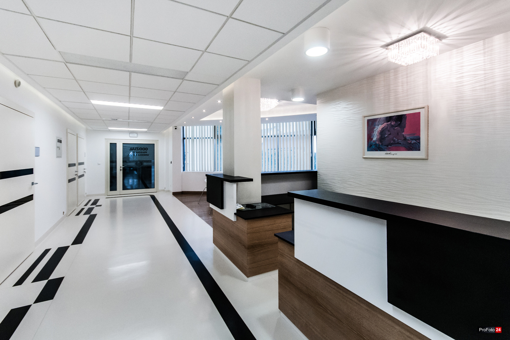 Nowoczesne wnętrze biurowe z białą podłogą z czarnymi akcentami, drewnianymi elementami wykończeniowymi, recepcją i oświetleniem LED.