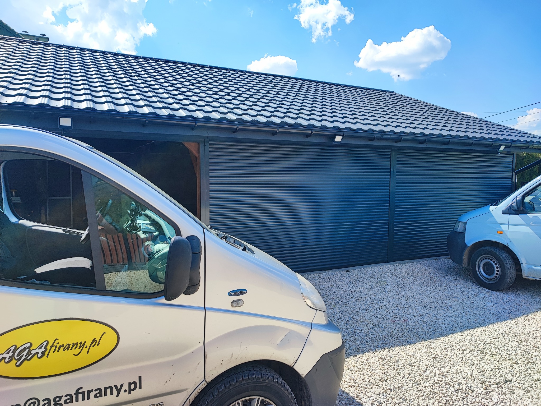 Zewnętrzna, pozioma osłona okienna w kolorze antracytowym, zamontowana na garażu, widoczna zza zaparkowanego samochodu dostawczego z żółtym logo firmy na boku.