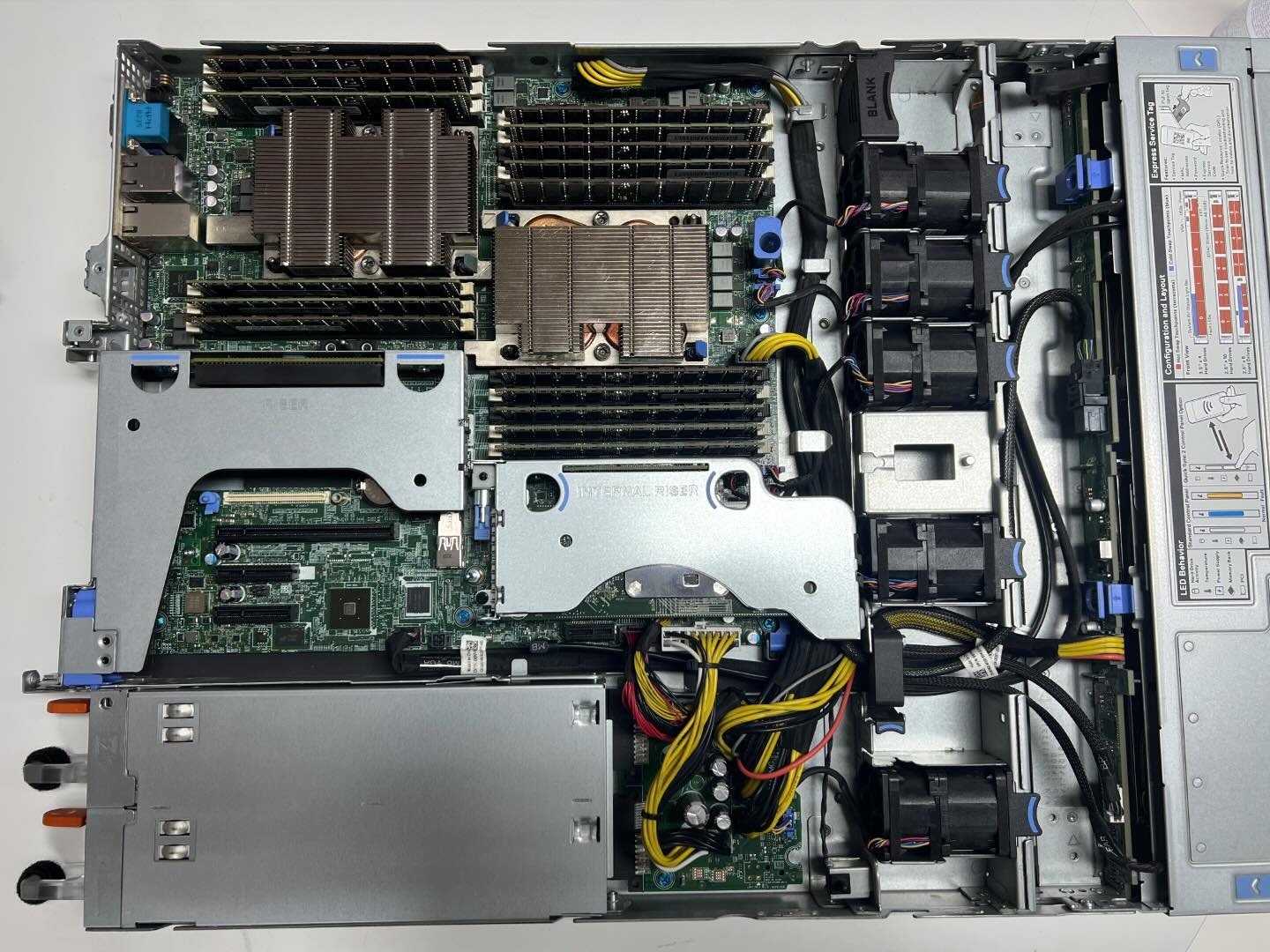 Wnętrze serwera z widocznymi procesorami z radiatorami, pamięcią RAM, kartą rozszerzeń, wentylatorami i okablowaniem, ukazujące złożoność jego budowy.