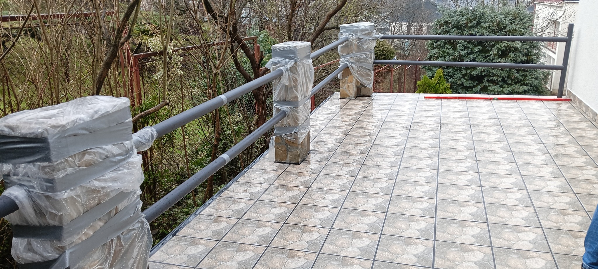 Świeżo wykafelkowany taras w Jarosławiu z zabezpieczonymi folią i taśmą słupkami balustrady, gotowy do dalszych prac wykończeniowych.