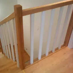 Fragment drewnianych schodów z białą balustradą w domu w Sosnowcu, widok z góry, jasne drewno stopni.