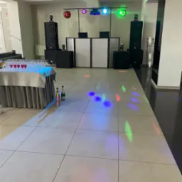 Sala bankietowa przed imprezą: nagłośnienie i oświetlenie ustawione, stół z kieliszkami i szampanem, parkiet oświetlony kolorowymi światłami.