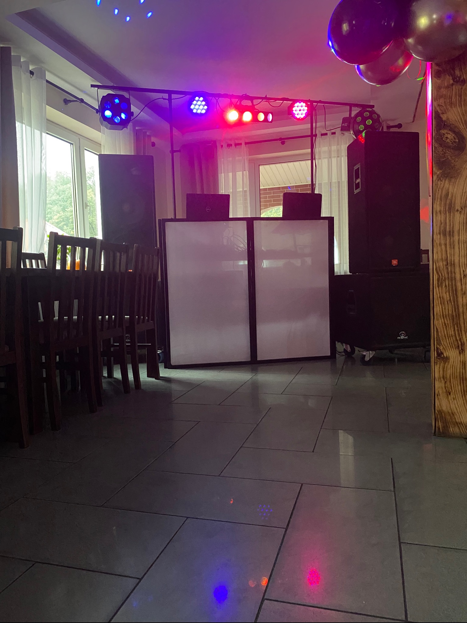 Sala z nagłośnieniem i oświetleniem dyskotekowym: kolumny, reflektory, konsoleta DJ-ska. Dekoracja balonowa. Przygotowanie do imprezy.