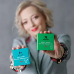 Kobieta prezentuje pudełka 'Let's talk' z hasłami 'Wakey-wakey! Morning class queries' i 'Look alive! Evening class queries' dla nauki angielskiego.